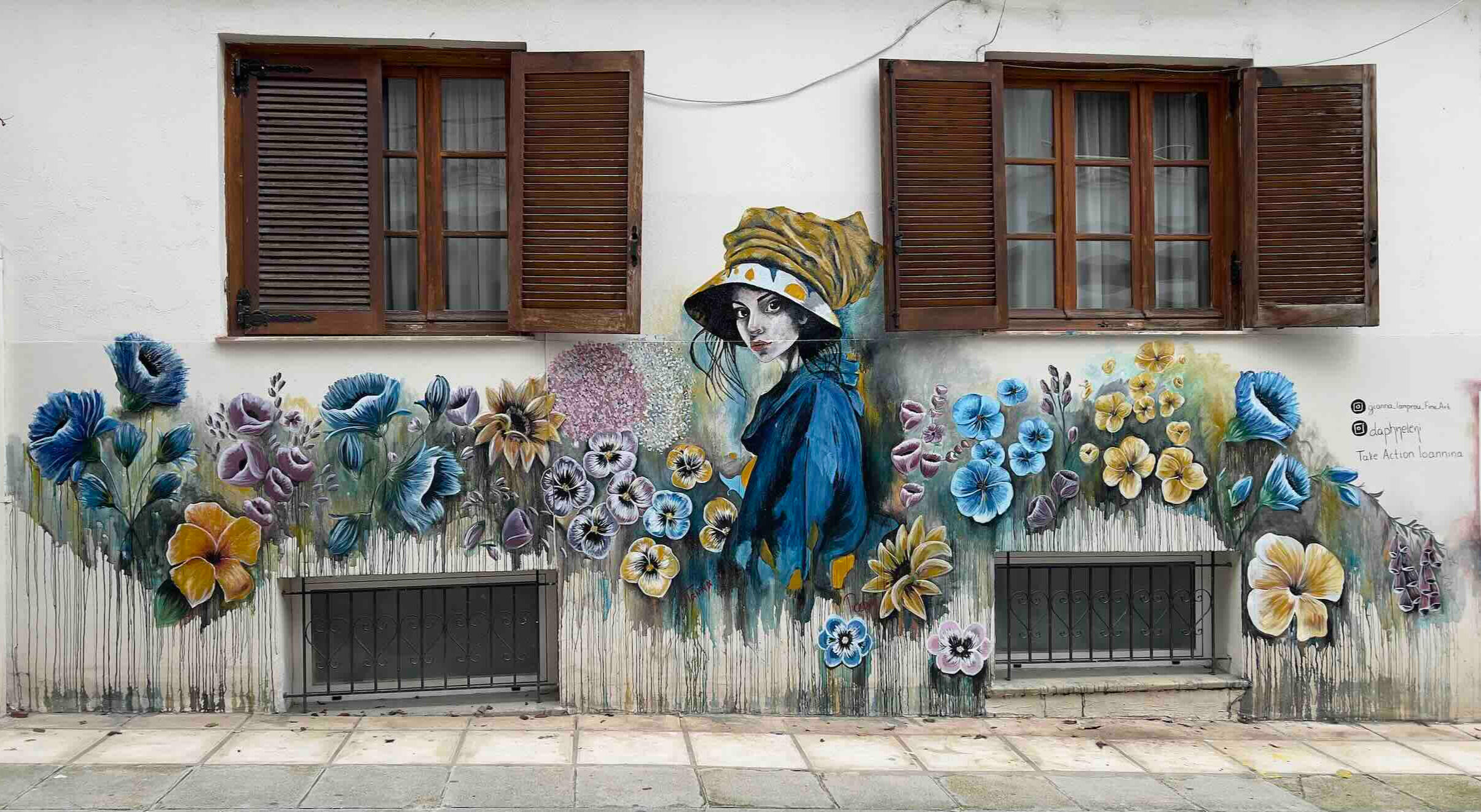 A group of volunteers wearing Take Action Ioannina t-shirts gather outside a cafe