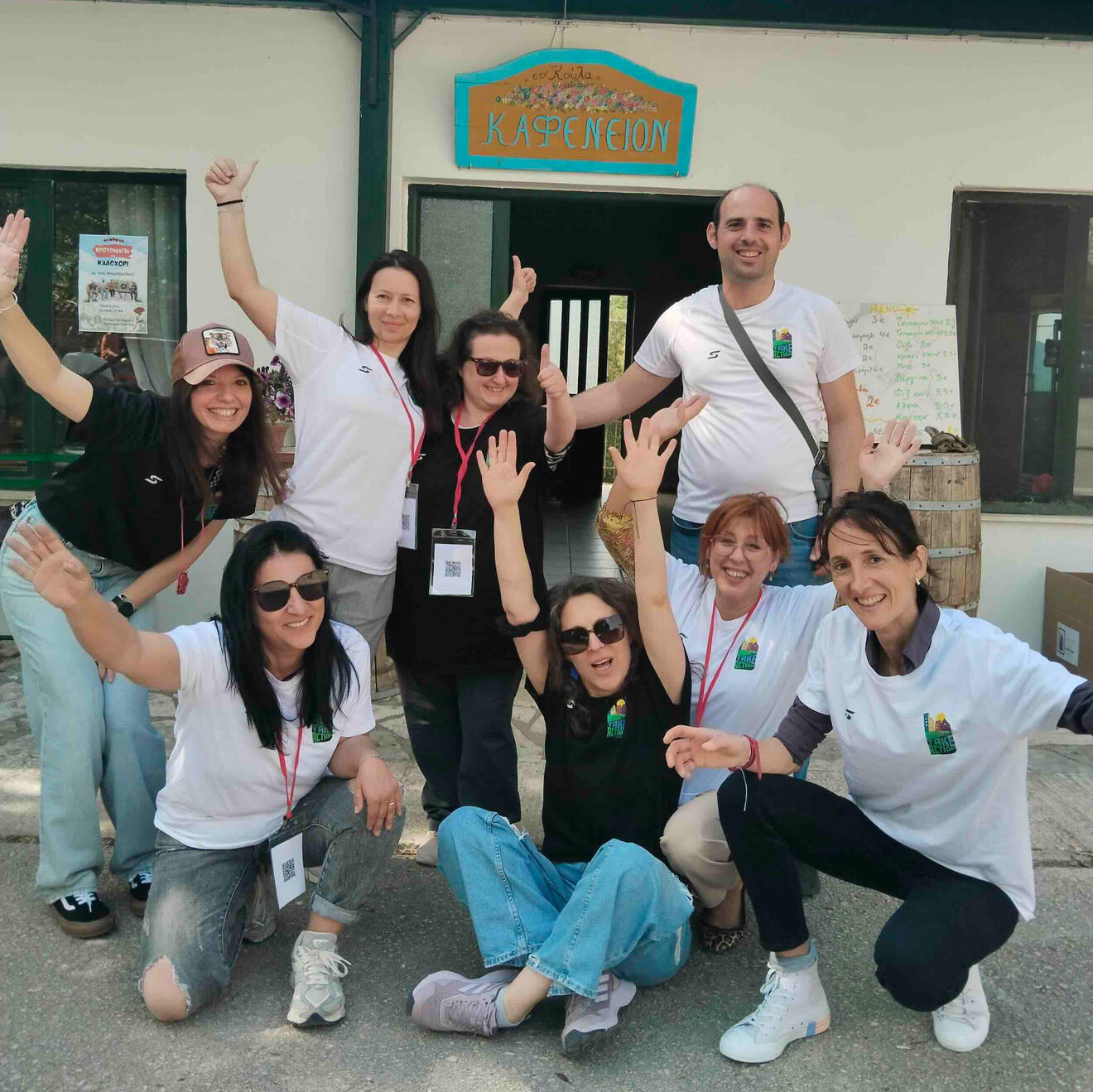 A group of volunteers wearing Take Action Ioannina t-shirts gather outside a cafe